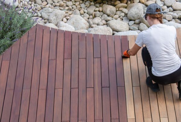 Hardwood deck oil application, overhead woman painting wood boards of garden decking
